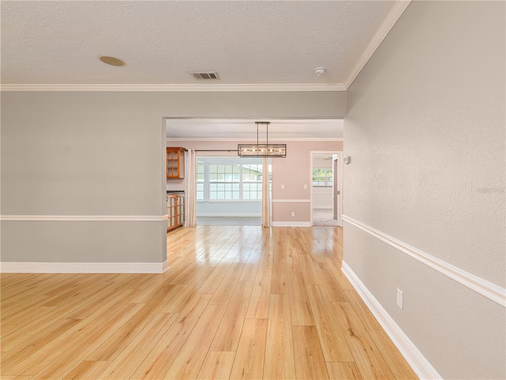 A view through a doorway into a dining area with light wood flooring and windows — 1661 ALGONQUIN DRIVE, CLEARWATER, FL
