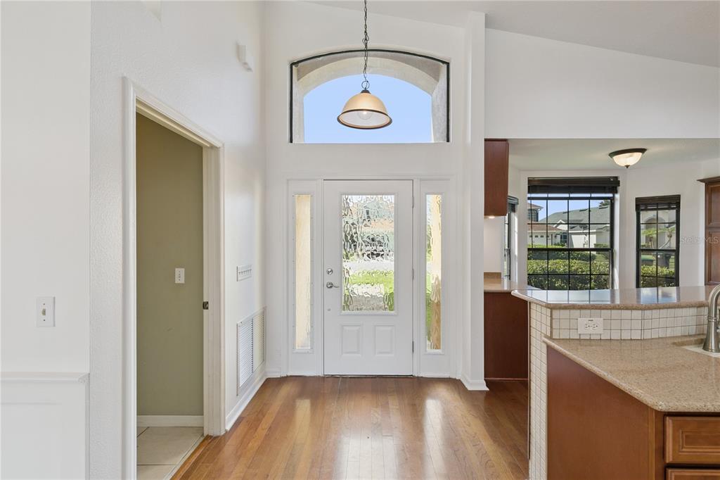 An entryway with hardwood floors, a white front door with sidelights, and a high arched window — 509 HARDWOOD CIRCLE, ORLANDO, FL
