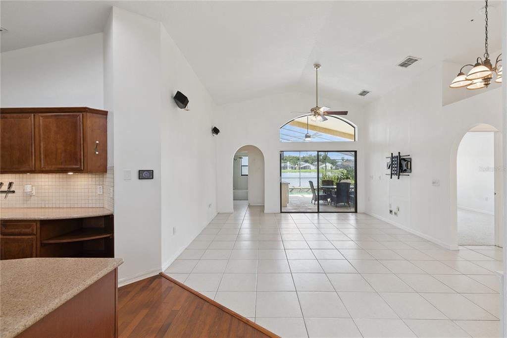 A bright living area with tile flooring, vaulted ceilings, and a sliding door to a patio — 509 HARDWOOD CIRCLE, ORLANDO, FL