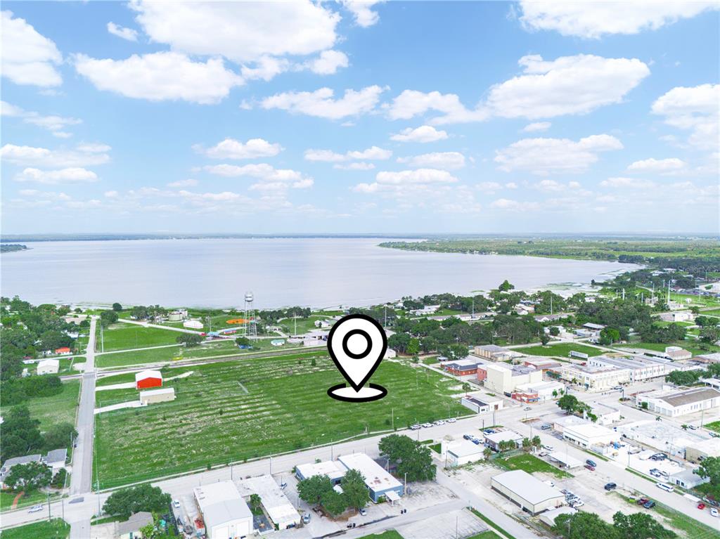 An aerial view shows a large, vacant grassy lot near a lake and town buildings — N SCENIC HIGHWAY, FROSTPROOF, FL