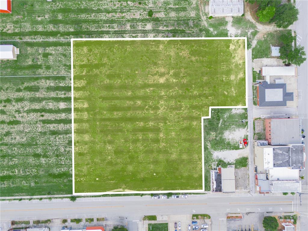An aerial view shows a large, vacant, L-shaped grassy lot outlined in white — N SCENIC HIGHWAY, FROSTPROOF, FL