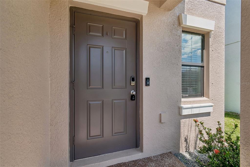 A two-story suburban house features a tan stucco exterior, a two-car garage, and palm trees — 13917 ARBOR PINES DRIVE, RIVERVIEW, FL