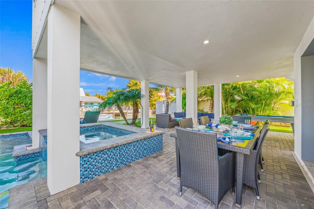 A covered patio features a tiled hot tub, a dining set, and a pool table — 401 20TH PLACE, BRADENTON BEACH, FL