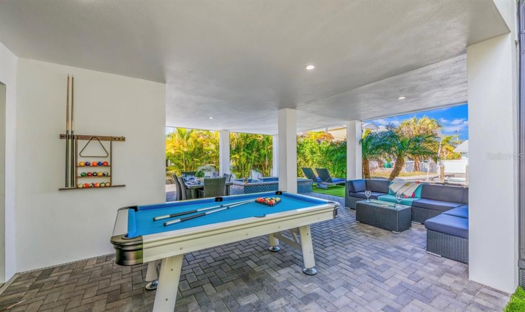 A covered outdoor patio features a pool table, lounge seating, and a dining area — 401 20TH PLACE, BRADENTON BEACH, FL
