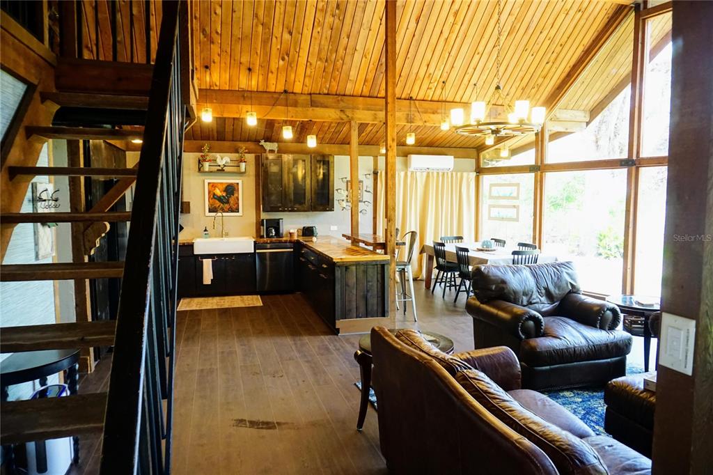 An open-concept living area features a kitchen with dark cabinetry, wood ceilings, and large windows — 6880 E CHANNEL DRIVE, HERNANDO, FL