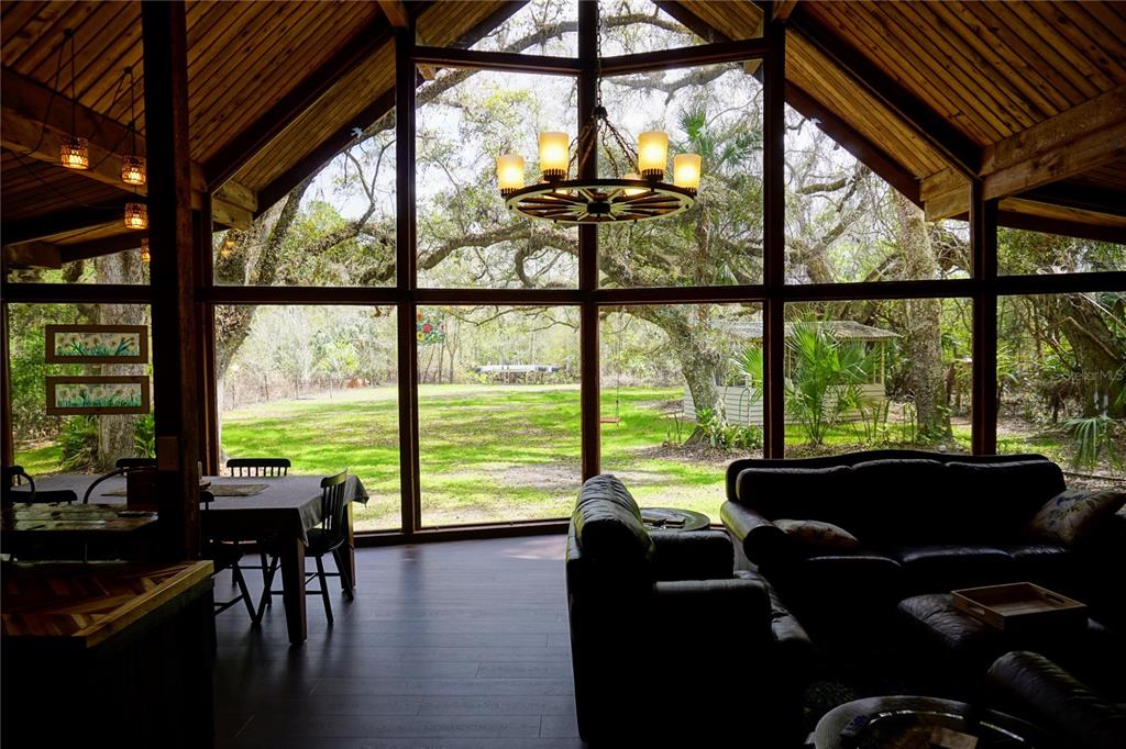 A living room with a vaulted wood ceiling, large windows, and a view of trees — 6880 E CHANNEL DRIVE, HERNANDO, FL