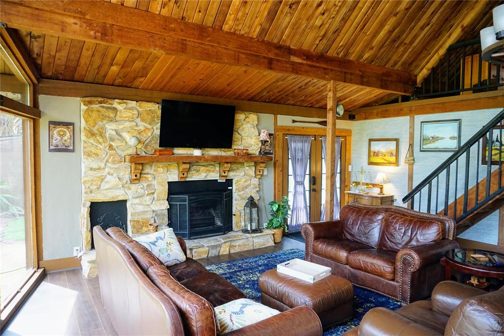 A living room features a stone fireplace, vaulted wood-paneled ceilings, and leather furniture — 6880 E CHANNEL DRIVE, HERNANDO, FL