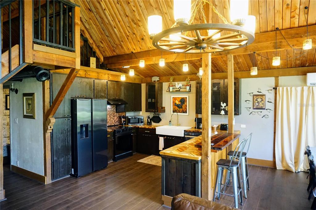 A rustic kitchen features dark wood cabinets, a farmhouse sink, and a wagon wheel chandelier — 6880 E CHANNEL DRIVE, HERNANDO, FL