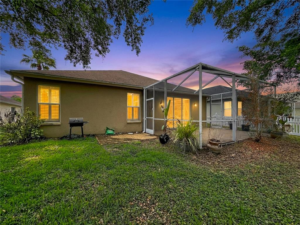 A screened-in patio with brick pavers and sliding glass doors leading into a house — 27509 EDENFIELD DRIVE, WESLEY CHAPEL, FL