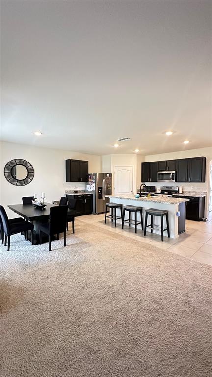 A kitchen features dark cabinets, granite countertops, a central island with a sink, and dining area — 476 BOARDWALK AVENUE, HAINES CITY, FL