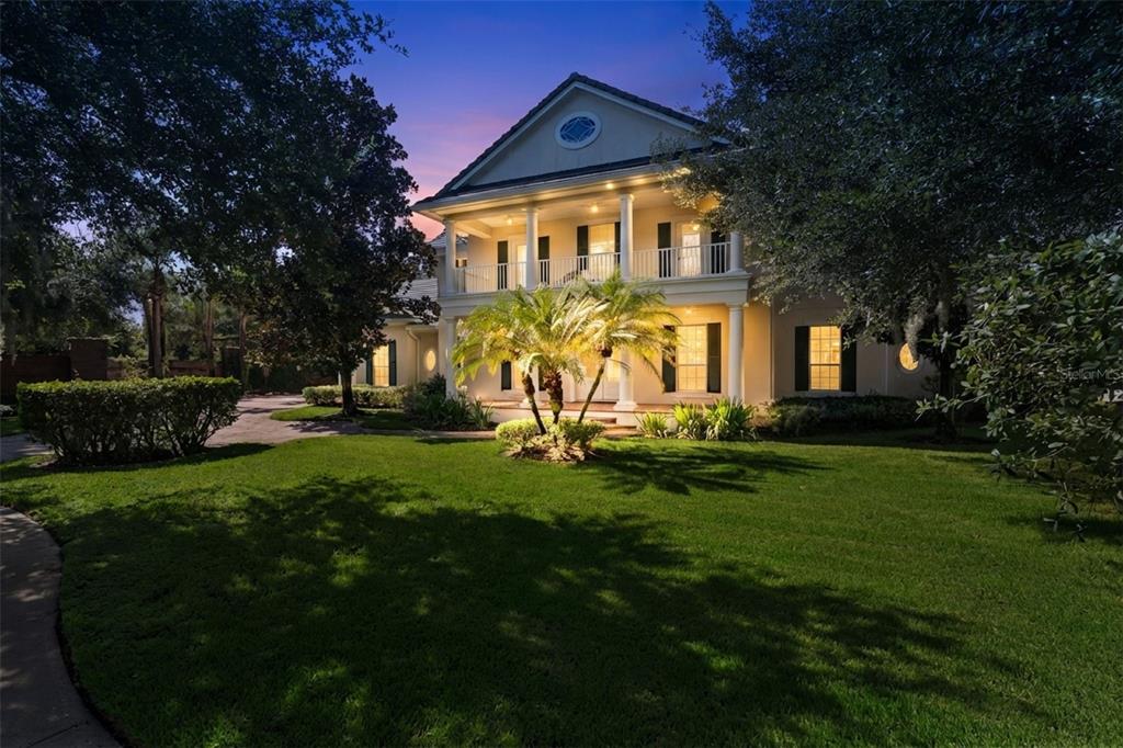 A two-story house with a columned front porch and balcony sits on a landscaped lawn — 1516 SUNSET POINTE PLACE, KISSIMMEE, FL