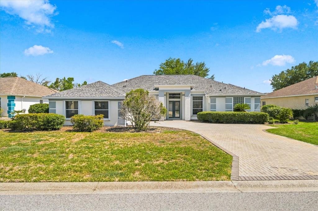 A single-story house with a paved driveway, light-colored stucco exterior, and a hip roof — 8402 MAYBELLE DRIVE, WEEKI WACHEE, FL