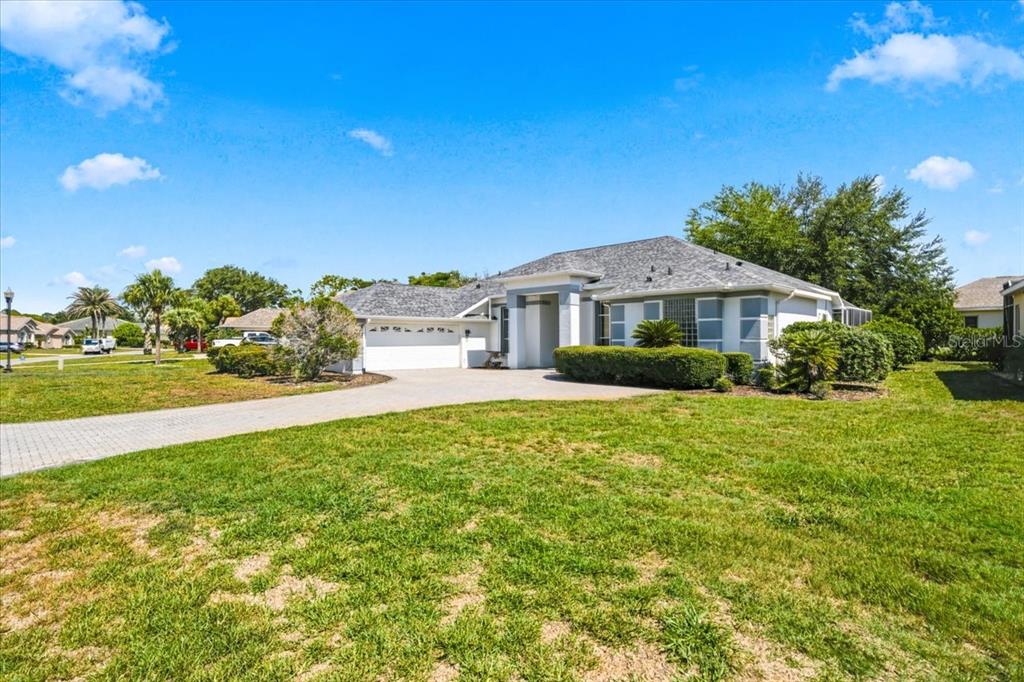 A single-story house with a paved driveway, white garage, and green lawn under blue sky — 8402 MAYBELLE DRIVE, WEEKI WACHEE, FL