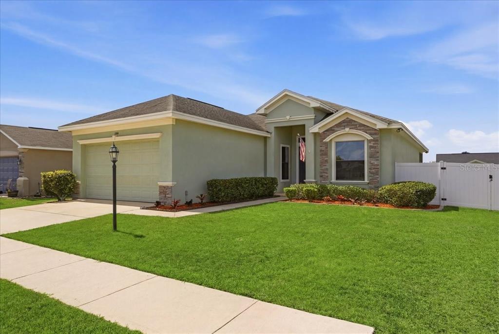 A single-story house with a green stucco exterior, a two-car garage, and a front lawn — 1789 KINGSMILL DRIVE, BARTOW, FL