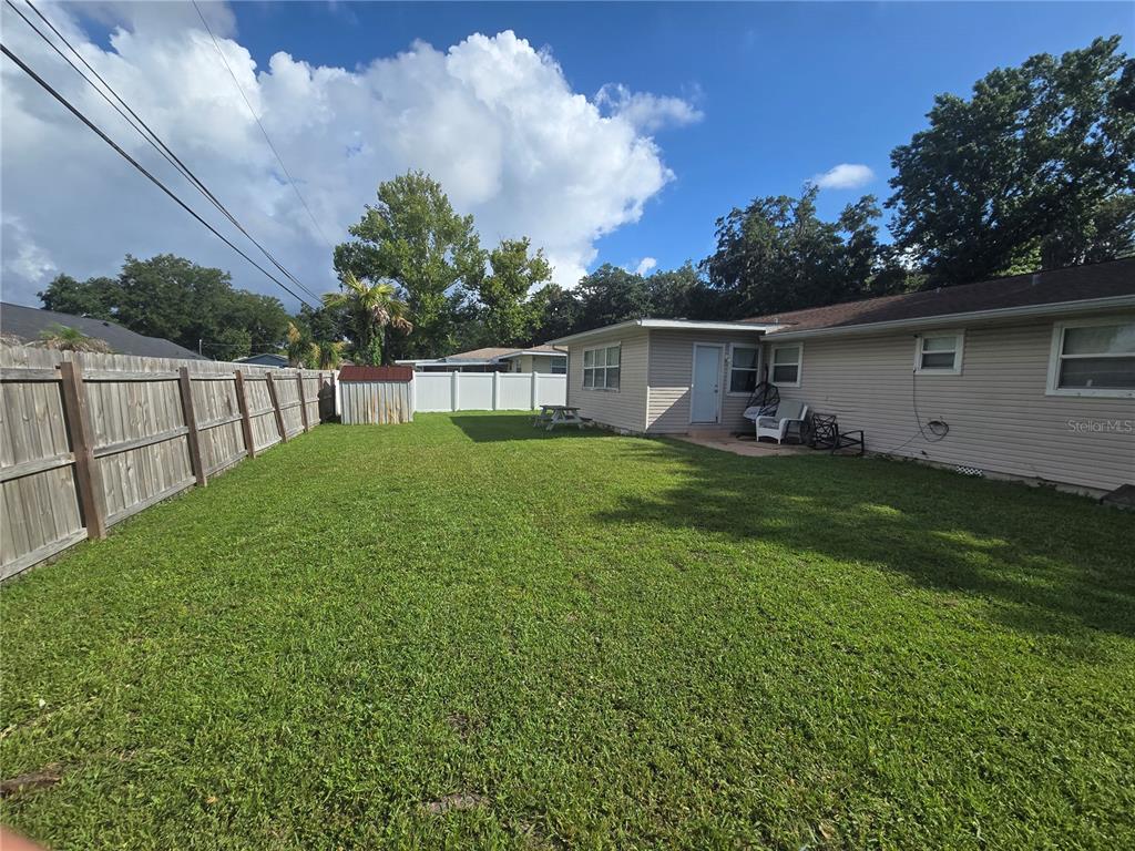 A grassy backyard features a wooden fence, a small shed, and a beige house exterior — 340 S CENTER STREET, ORMOND BEACH, FL