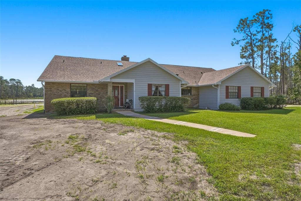 A single-story house with tan siding, a brick facade, and a concrete walkway — 349 SEMINOLE WOODS BLVD, GENEVA, FL