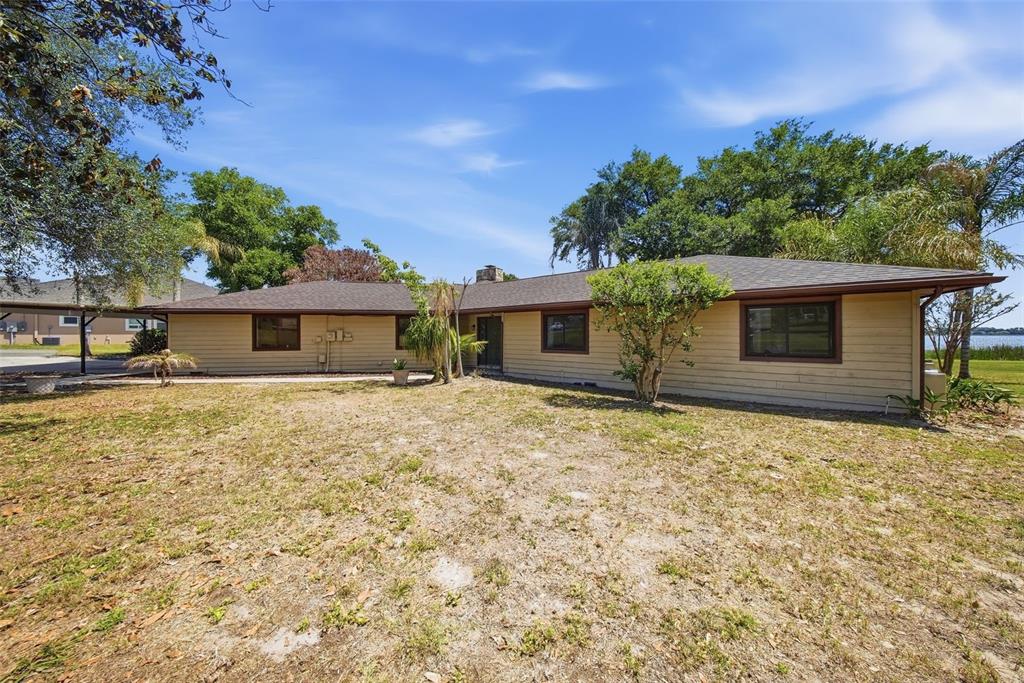 A single-story house with beige horizontal siding and a dark roof sits on a lot — 410 S RAMONA AVENUE, LAKE ALFRED, FL