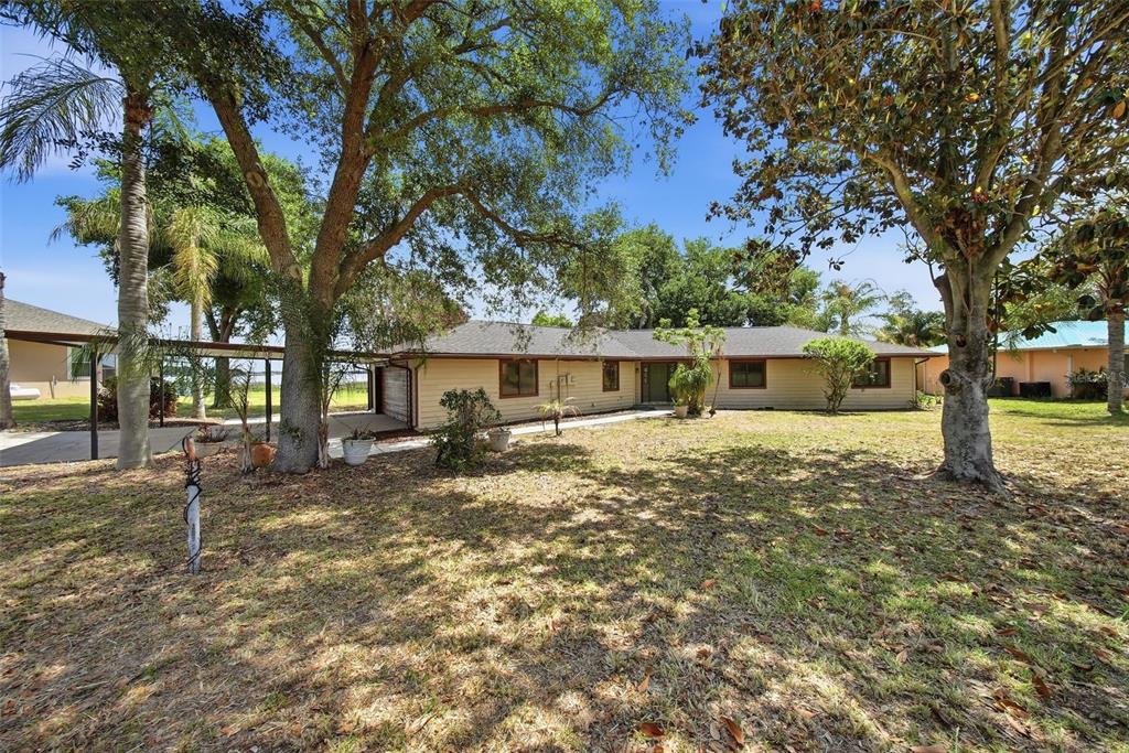 A single-story house with light-colored siding and a dark shingled roof sits on a lawn — 410 S RAMONA AVENUE, LAKE ALFRED, FL