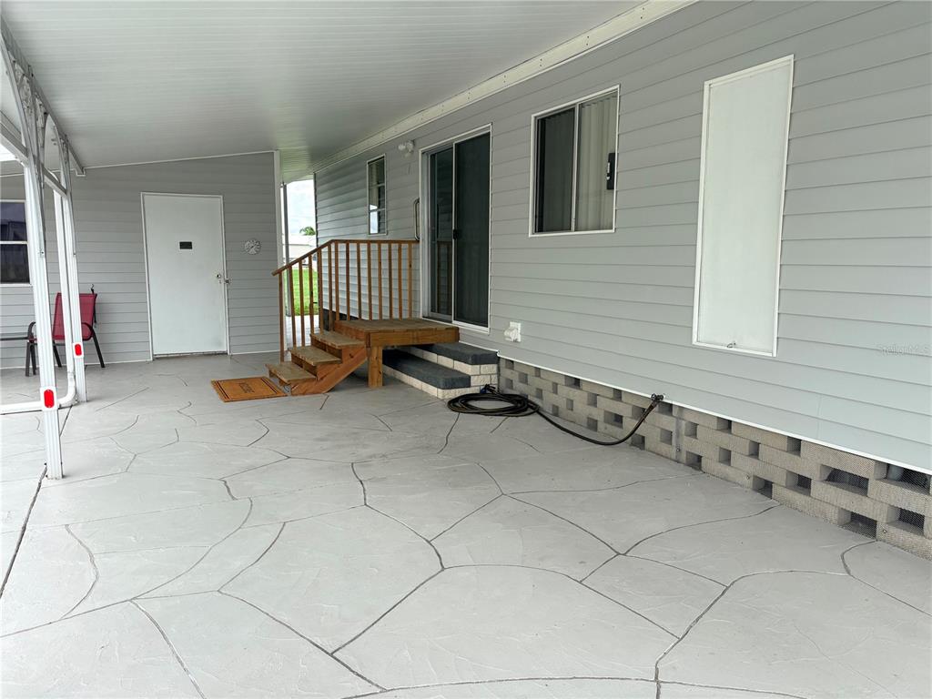 A covered patio with a concrete floor, wooden steps, and gray horizontal siding — 3163 INDIAN VILLAGE LANE, NORTH FORT MYERS, FL