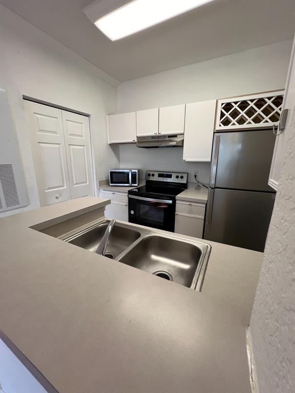 A kitchen features white cabinets, stainless steel appliances, a double sink, and a breakfast bar — 2674 ROBERT TRENT JONES DRIVE UNIT 334, ORLANDO, FL