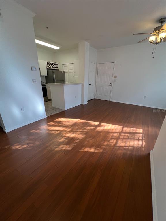 An open living area features hardwood floors, a ceiling fan, and an adjacent kitchen — 2674 ROBERT TRENT JONES DRIVE UNIT 334, ORLANDO, FL