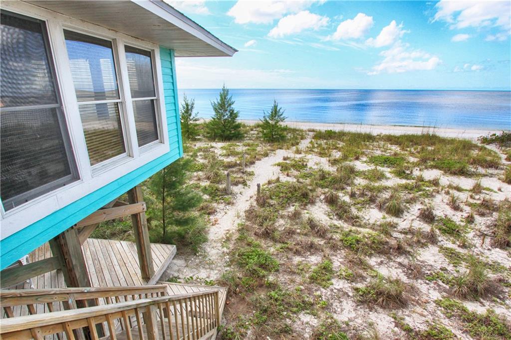 An elevated turquoise house overlooks a sandy path leading to the beach and ocean — 181 N GULF BOULEVARD UNIT 4, PLACIDA, FL