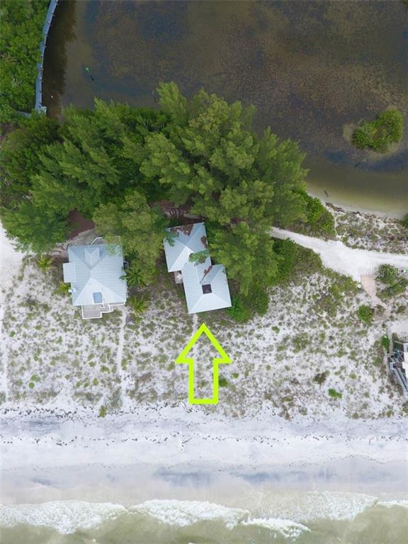 An aerial view shows two houses nestled among trees on a sandy beach near water — 181 N GULF BOULEVARD UNIT 4, PLACIDA, FL