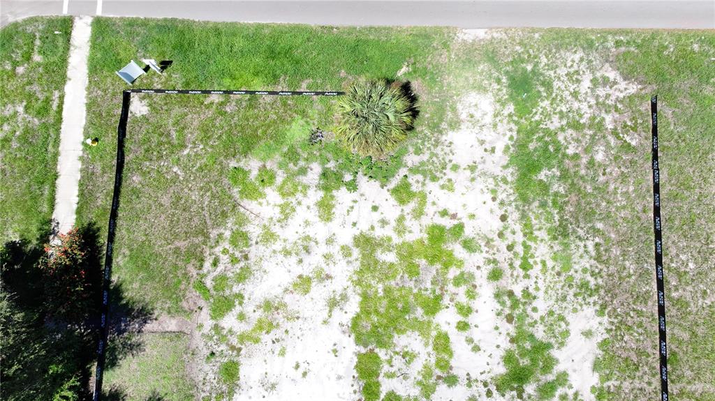 An aerial view shows a vacant, grassy residential lot marked by black silt fencing — 5631 23RD AVENUE S, GULFPORT, FL