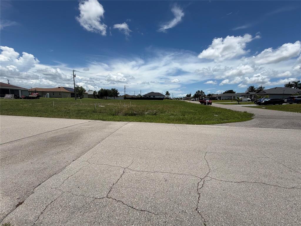 A vacant grassy residential lot sits at the corner of two paved suburban streets — 2829 NE 5TH AVENUE, CAPE CORAL, FL