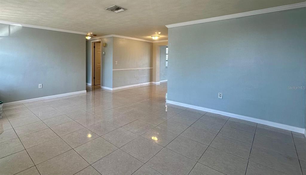 An open-concept living area features light blue walls, white crown molding, and glossy tile flooring — 12812 4TH ISLE, HUDSON, FL