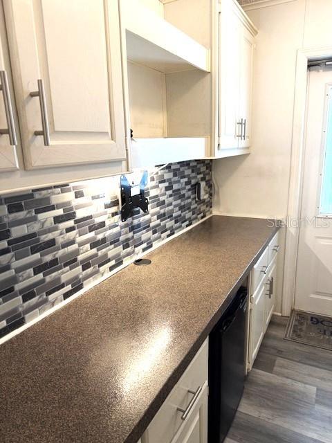 A kitchen features light-colored cabinets, a dark countertop, and a gray-toned mosaic tile backsplash — 1001 STARKEY RD. UNIT # 731, LARGO, FL