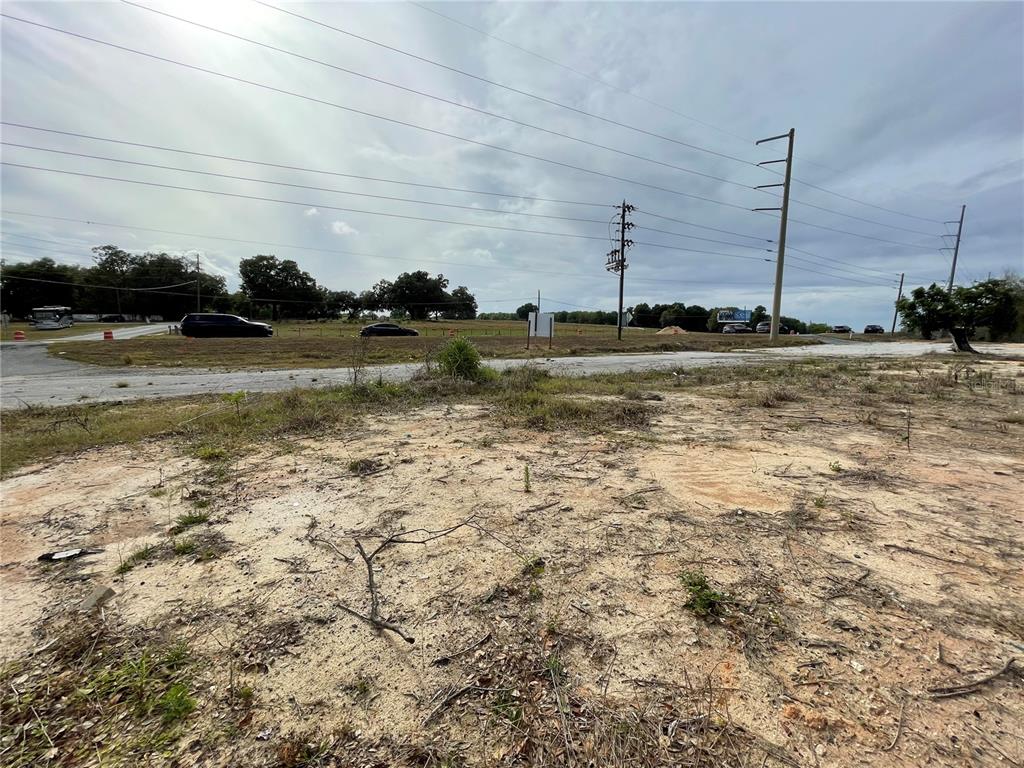A view of a vacant, sandy lot with power lines and a road in the distance — 2011 US HIGHWAY 441/27, FRUITLAND PARK, FL