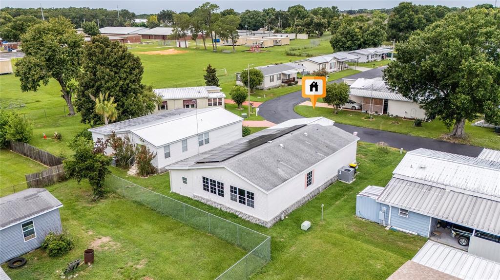 An aerial view shows several mobile homes with metal roofs situated on a grassy lot — 149 JANA CIRCLE, AUBURNDALE, FL
