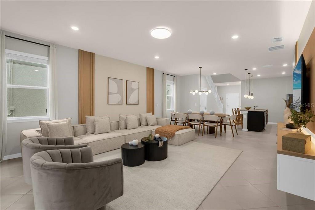 A modern open-concept living and dining area features light tile flooring and neutral furniture — 16225 SAINT KITTS CIRCLE, CLERMONT, FL