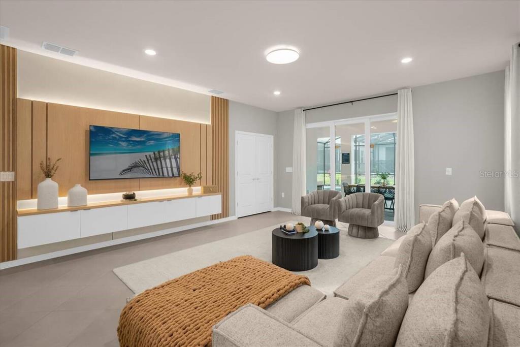 A modern living room features a wood-paneled media wall, a floating console, and neutral furniture — 16225 SAINT KITTS CIRCLE, CLERMONT, FL
