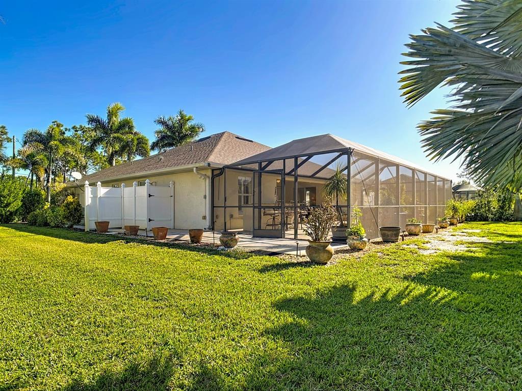 A house exterior features a screened-in lanai, a white privacy fence, and a grassy lawn — 101 & 103 WAHOO DRIVE, ROTONDA WEST, FL
