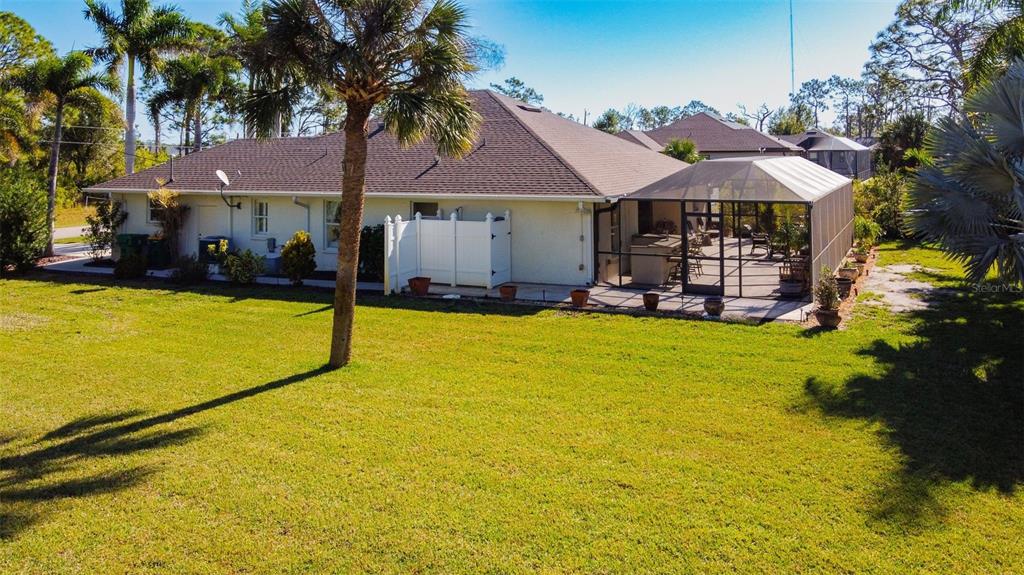 The exterior of a single-story house features a screened-in patio and a large grassy yard — 101 & 103 WAHOO DRIVE, ROTONDA WEST, FL