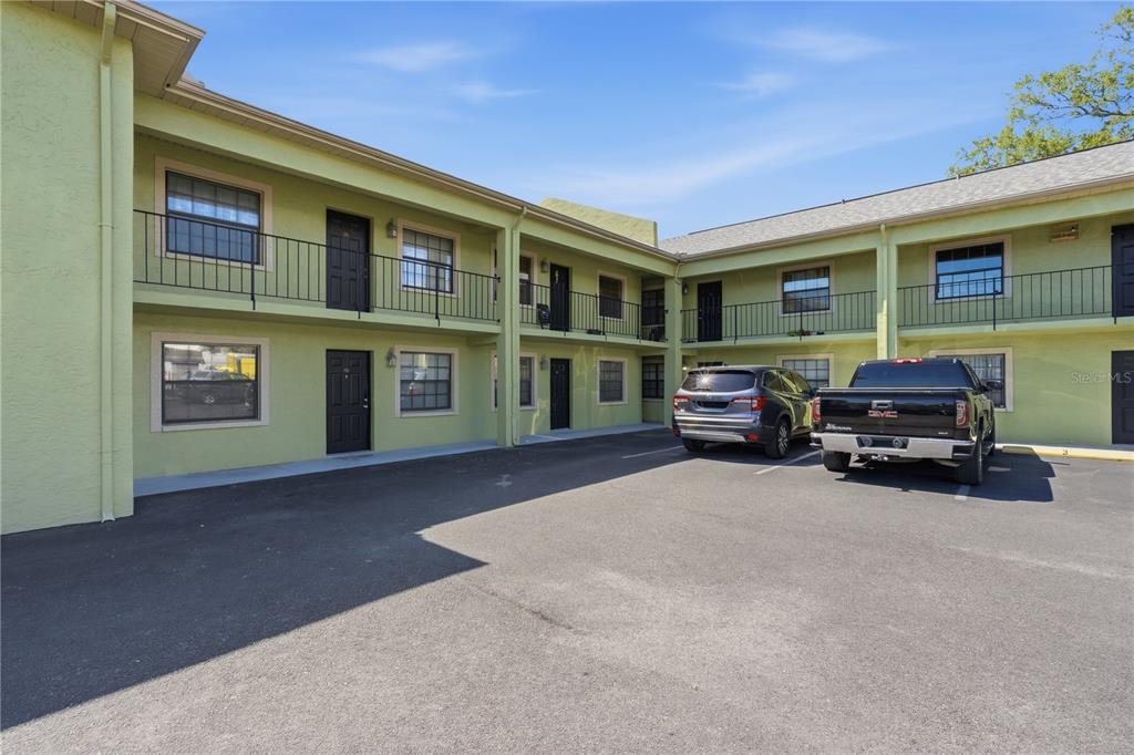 A two-story apartment building with a parking lot and two parked vehicles in front — 4416 N CLARK AVENUE UNIT 13, TAMPA, FL
