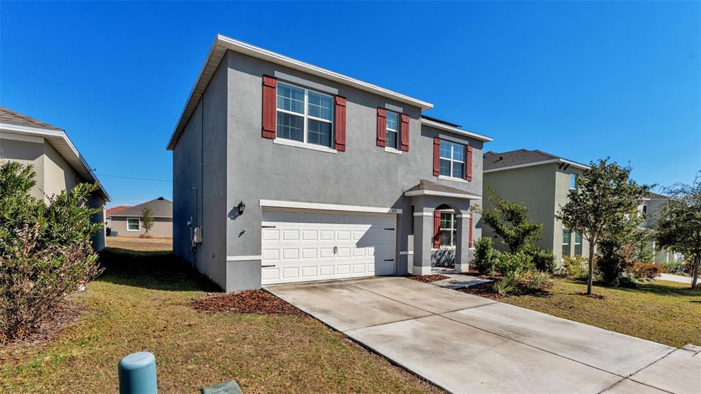 A two-story gray stucco house features a white garage door and red window shutters — 209 SOFIA LANE, LAKE ALFRED, FL