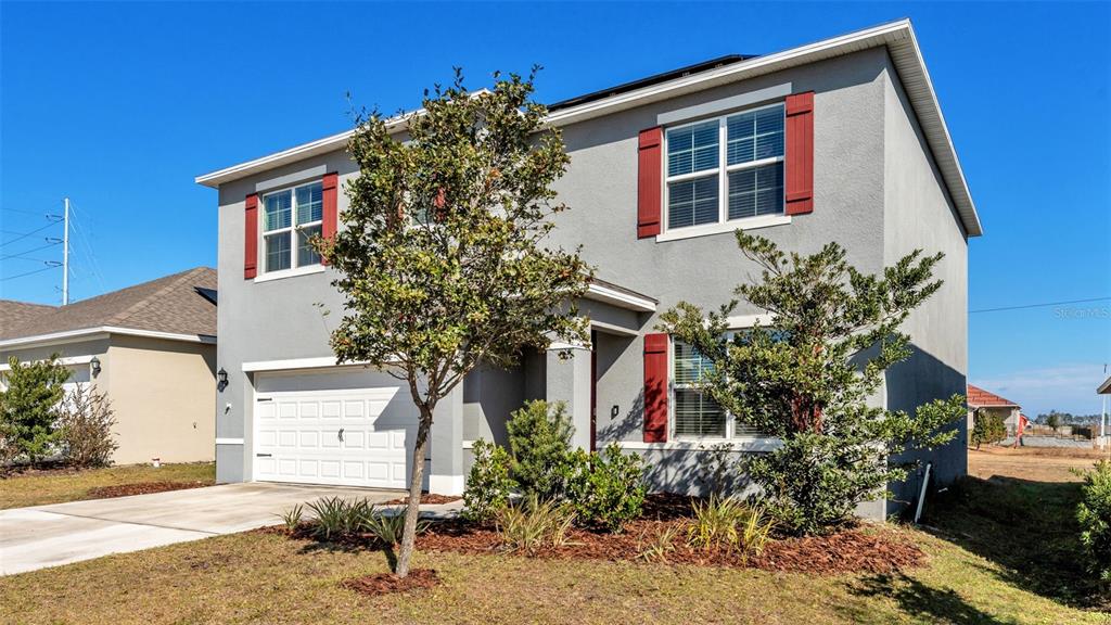 A two-story gray house with red shutters and a two-car garage under a clear sky — 209 SOFIA LANE, LAKE ALFRED, FL