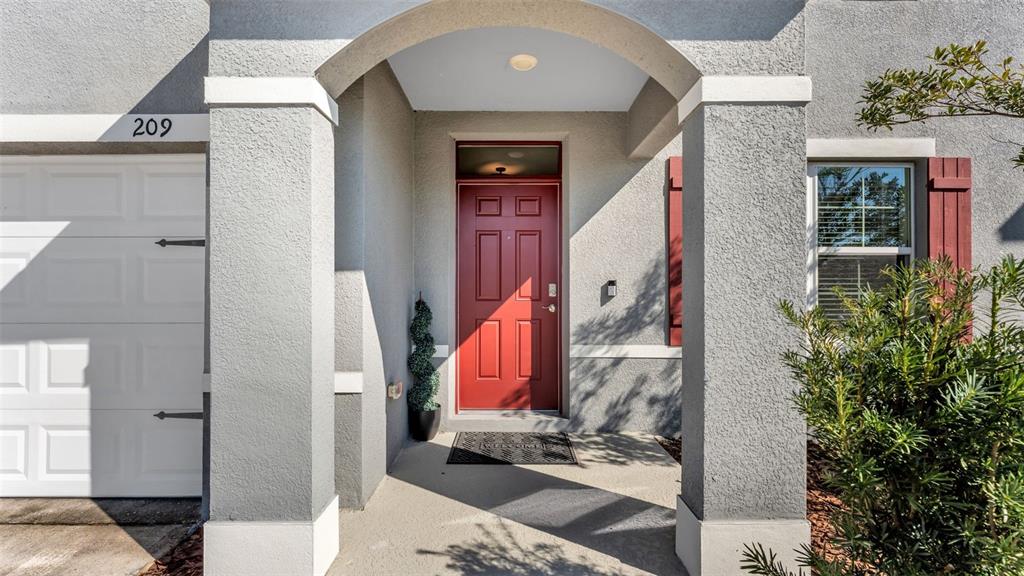 The exterior view shows a house entrance with a red door, gray stucco, and columns — 209 SOFIA LANE, LAKE ALFRED, FL