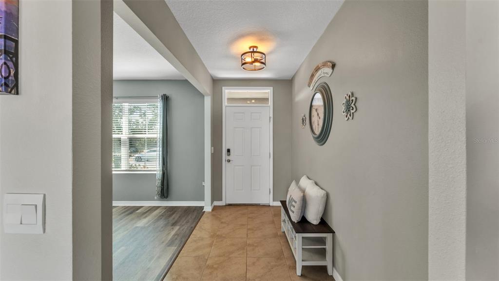 An entryway features tile flooring, a white front door, and a bench against the wall — 209 SOFIA LANE, LAKE ALFRED, FL
