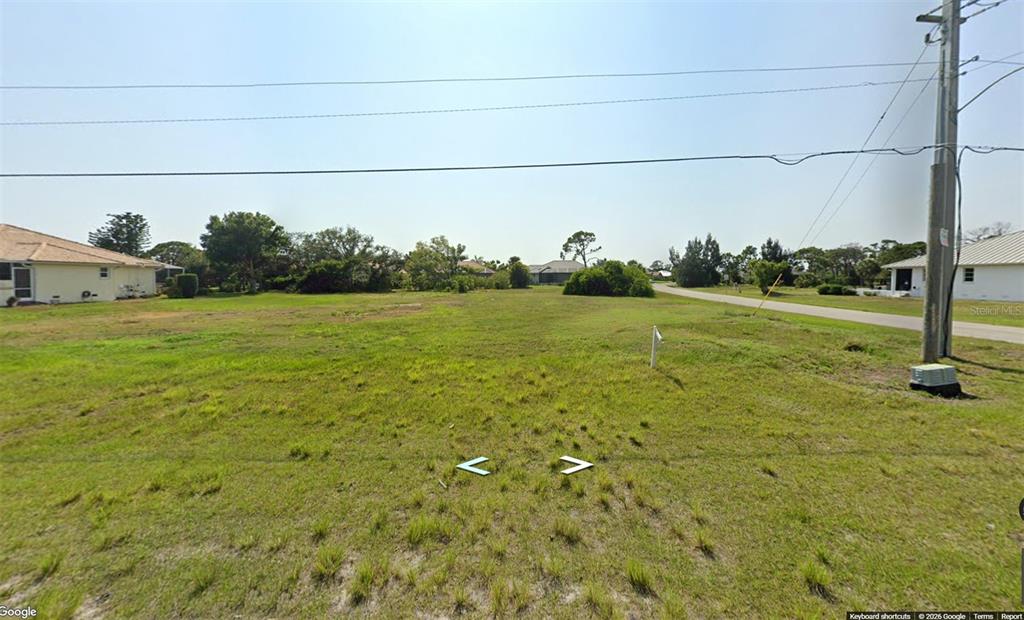 A vacant, grassy residential lot sits between two houses along a paved road — 4190 CAPE HAZE DRIVE, PLACIDA, FL