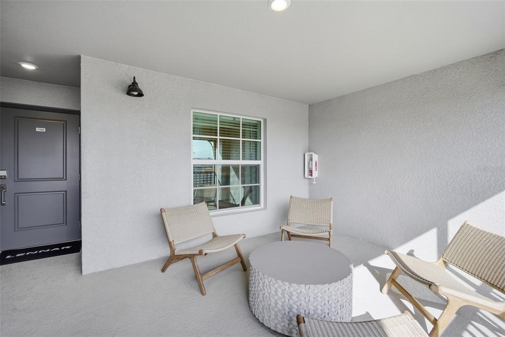 A covered patio features light gray walls, a window, and four chairs around a round table — 18911 SCALLOP LOOP UNIT 205, LAKEWOOD RANCH, FL