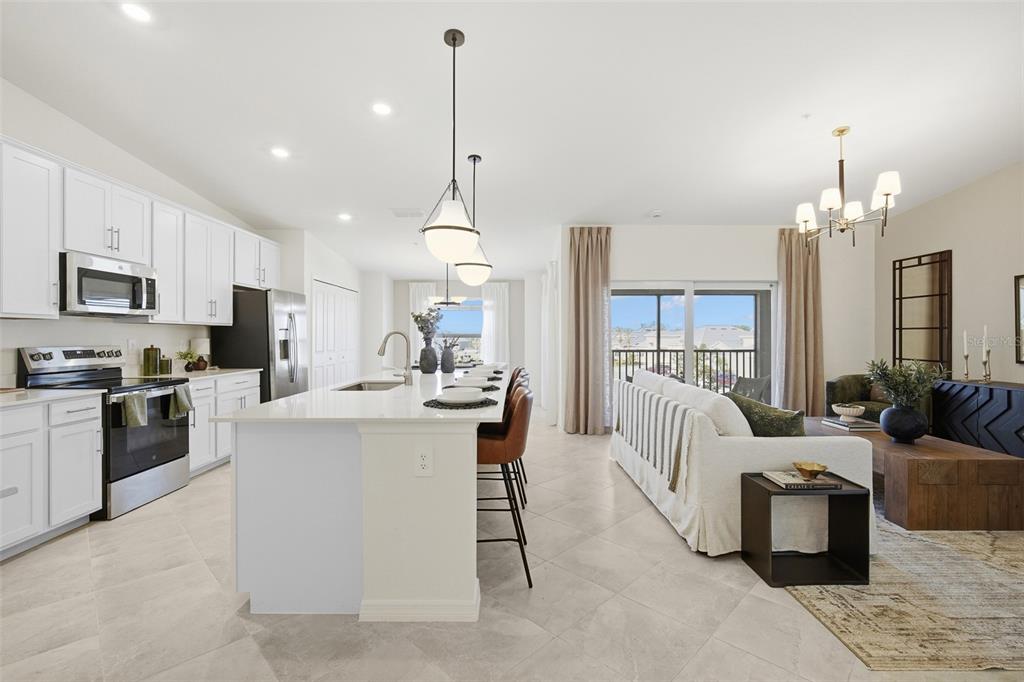 A bright open-concept kitchen and living area with white cabinets, a large island, and balcony — 18911 SCALLOP LOOP UNIT 205, LAKEWOOD RANCH, FL