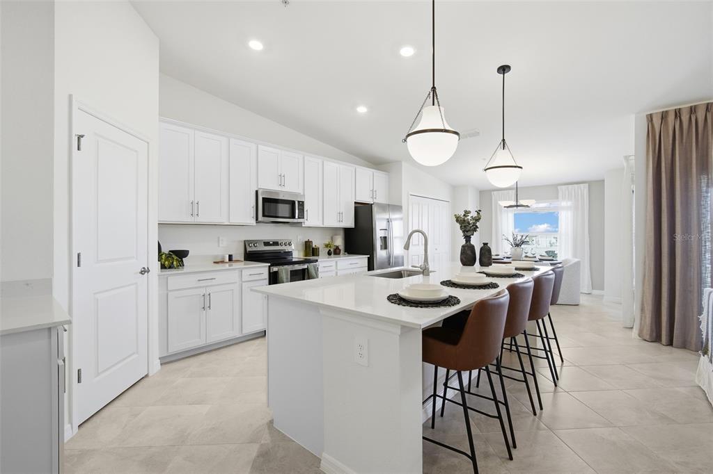 A modern kitchen with white cabinets, a large island, and bar stools — 18911 SCALLOP LOOP UNIT 205, LAKEWOOD RANCH, FL