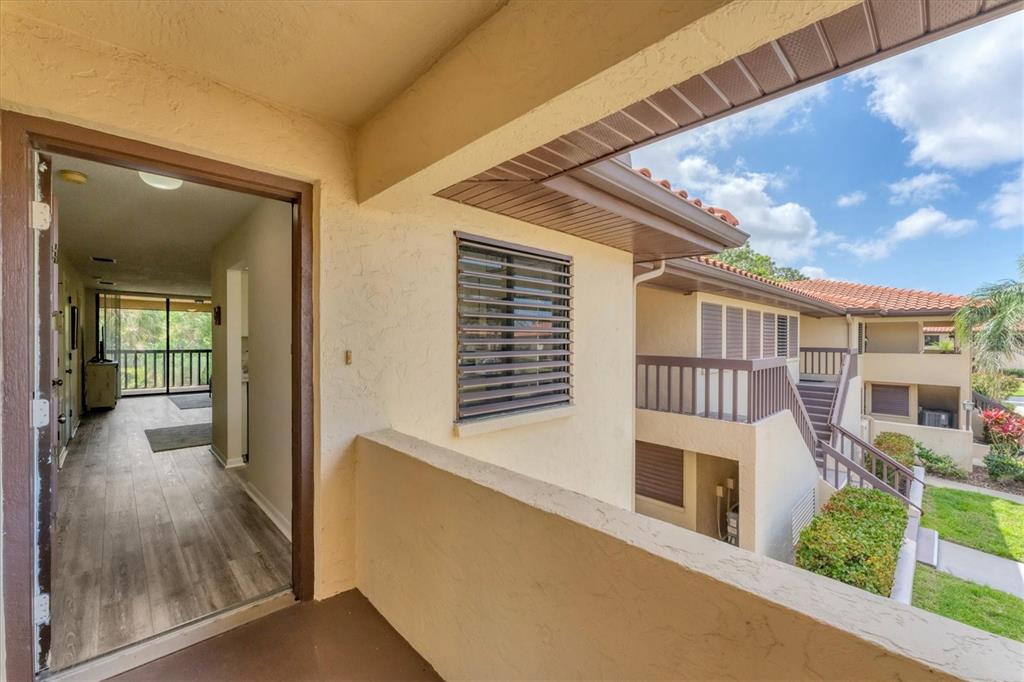 An exterior view of a balcony looking into an apartment with wood-look flooring — 5264 LAKE VILLAGE DRIVE UNIT 48, SARASOTA, FL