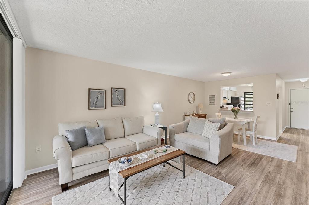 A living room features a beige sofa, matching armchair, coffee table, and light wood flooring — 5264 LAKE VILLAGE DRIVE UNIT 48, SARASOTA, FL