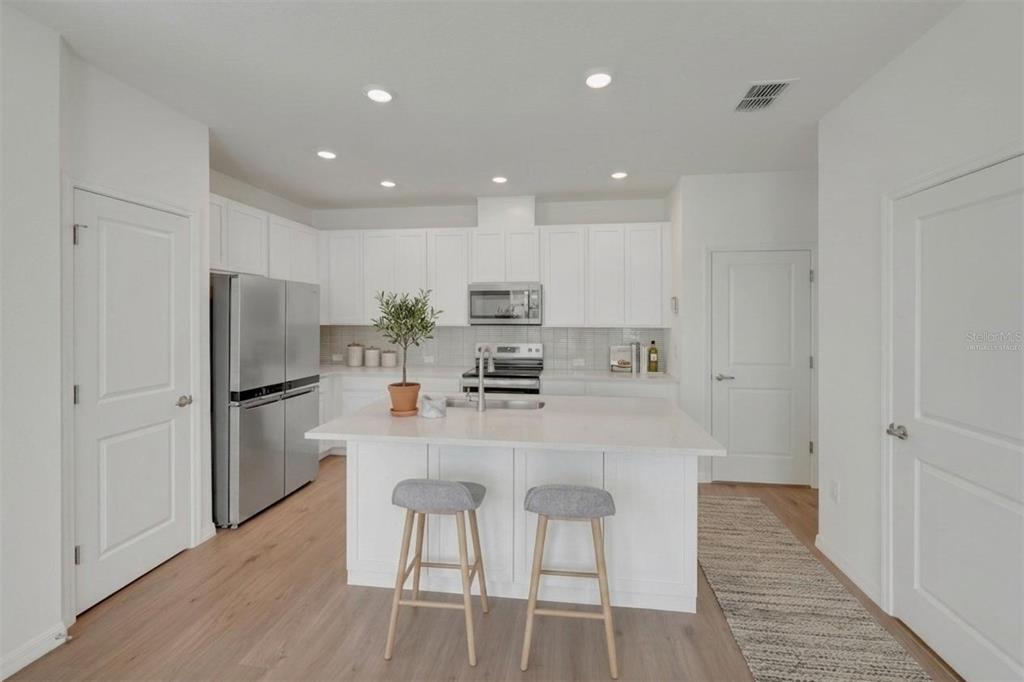 A two-story duplex with white siding, two garage doors, and a concrete driveway at dusk — 6418 JENSEN VIEW AVENUE, APOLLO BEACH, FL