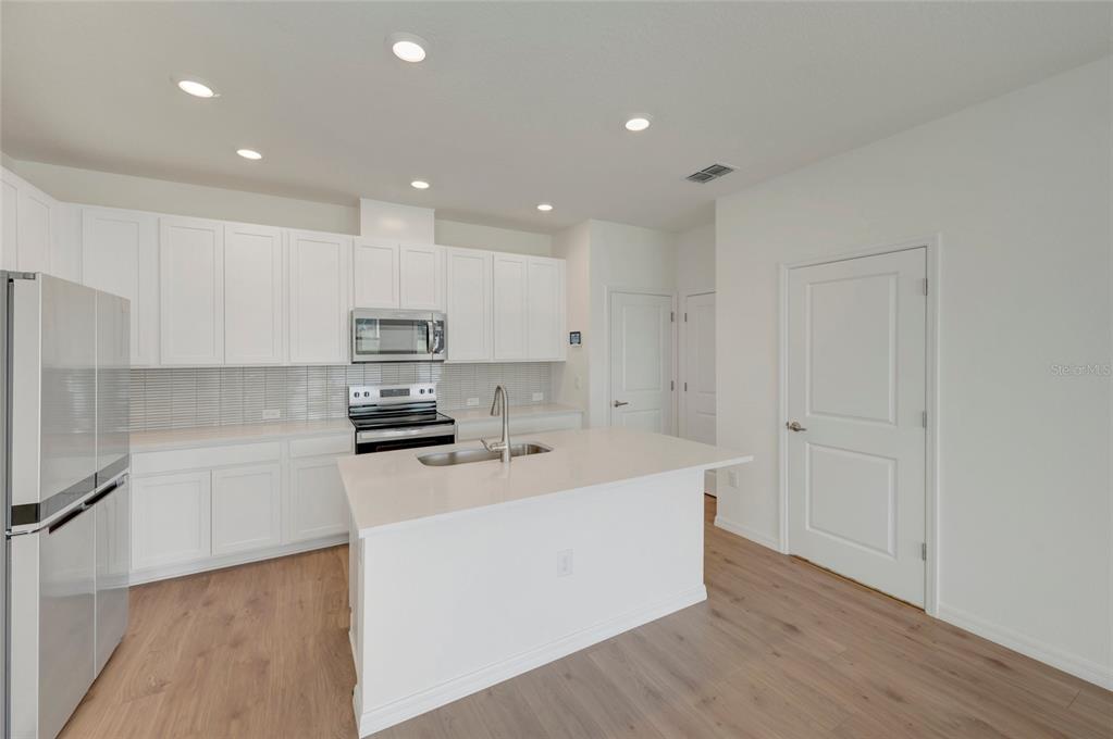 This is a floor plan of a home's first level featuring a garage and open-concept living — 6418 JENSEN VIEW AVENUE, APOLLO BEACH, FL